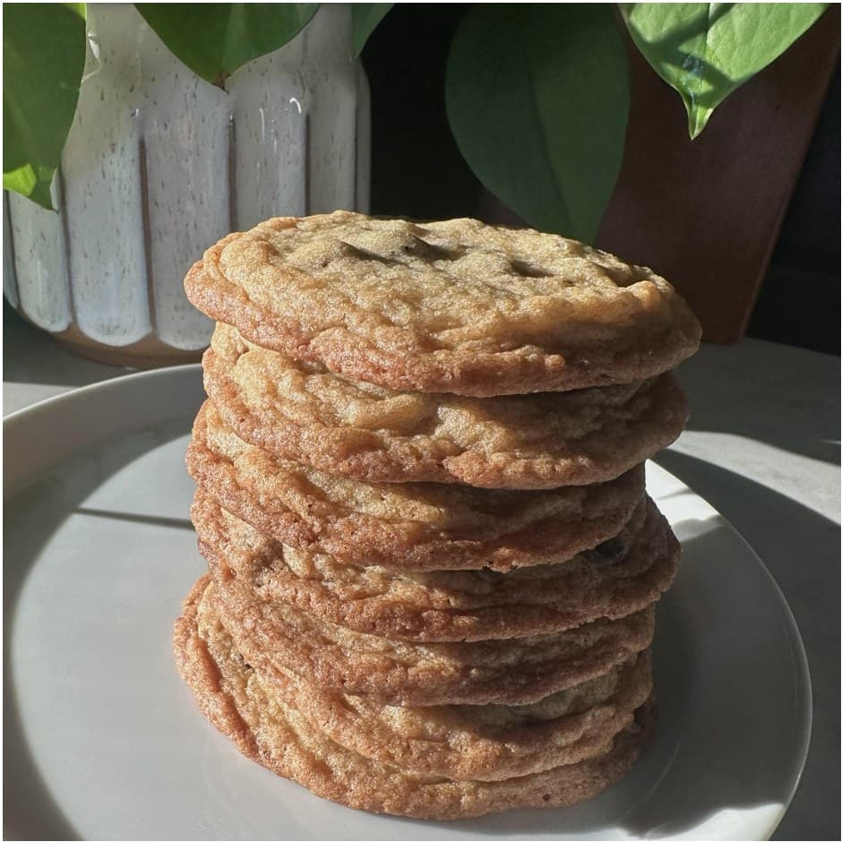 A tall stack of homemade cookies on a white plate in afternoon light